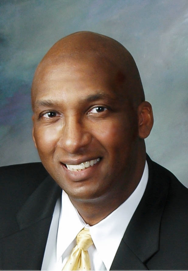 Professional executive headshot — man in dark suit with confident smile